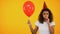 Upset female holding balloon and blowing party horn, feeling lonely on birthday