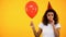 Upset female holding balloon and blowing party horn, feeling lonely on birthday