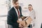 Upset fired businessman with cardboard box and angry businesswoman in office