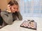 Upset girl play chess at table