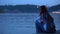 Upset girl sitting on river embankment enjoying calm water and fresh evening air