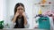 Upset housewife looking at camera, laundry basket full of clothes on table