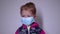 Upset little blonde girl in a blue medical mask. in a pink sweater. covid 19 pandemia. kids on isolation. FullHD footage