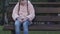 Upset little girl sitting on bench in park, feels lonely, lack of communication