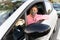 Upset looking woman with face mask leaning arm on car window