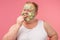 Upset man with cucumber clay mask on face taking a slice of cucumber on taste.