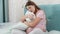 Upset pregnant woman sitting on bed and hugging big pillow. Concept of maternal and pregnancy depression.