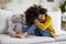 Upset preteen black girl sitting on couch with teddy bear