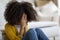 Upset preteen black girl sitting on floor at home, crying