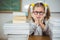 Upset pupil between stack of books on her desk