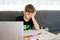 Upset school kid boy making homework during quarantine time from corona pandemic disease. Frustrated sad boy learning