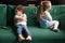 Upset siblings sitting on sofa ignoring each other after fight