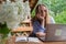 Upset sleepy Female student has online lesson education outdoor in garden wooden alcove. Blonde woman sitting outside