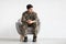 Upset soldier sitting at armchair over white background