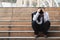 Upset stressed young Asian business man in suit with hands on head sitting on stairs. Unemployment and layoff concept