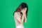 Upset stressed young Asian woman with hands on face feeling disappointed on green isolated background