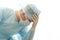 Upset surgeon in sterile gown and surgical mask props his head with hand