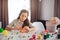 Upset teenager prepare for Easter alone. She sit at table and painting eggs. Girl wear rabbit ears. Colorful sweets and