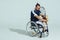 Upset tennis player sitting in wheelchair and holding tennis racquet and ball