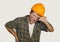 Upset and tired construction worker or repair man wearing builder helmet complaining suffering pain in his lower back feeling