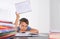 Upset tired preteen child sitting at the table, doing his homework among pile of books. Word Help is written on open