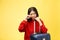 Upset tourist woman in summer casual clothes sit on suitcase put hands on head isolated on yellow orange background