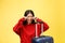 Upset tourist woman in summer casual clothes sit on suitcase put hands on head isolated on yellow orange background