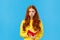 Upset and uneasy, sad cute redhead girl in yellow sweater, sulking frowning and looking camera depressed, holding red
