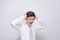 Upset unhappy young man in white t-shirt squeezing head with hands, suffering from headache. People, stress, tension and migraine