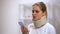 Upset woman In foam cervical collar looking at smartphone, received bad news