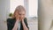 Upset woman sitting at workplace. Blond sad female in elegant clothes clutching head after failure or bad news sitting