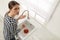 Upset woman using plunger to unclog sink drain in kitchen, above view