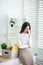 Upset young brunette female sitting on her desk, touching her nose bridge