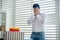 Upset young brunette male standing at the window, covering his face with his hands