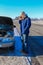 Upset young man calling the car service standing near a broken car at winter road