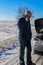 Upset young man calling the car service standing near a broken car at winter road