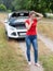 Upset young woman broke car in the field and calling for help