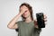 Upset young woman holding her broken smartphone. Phone screen need to repair