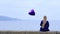 Upset young woman holding violet heart balloon.