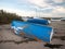 Upside down blue chipped painted private boat moored on beach
