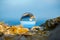 Upside down seascape with blue sky and overgrown with moss rocks - reflection in a lens ball