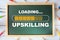 Upskilling loading written on chalkboard with coloured pencil on wooden