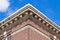 Upward view of a 19th Century red and white brick wall with cornice