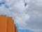 Upward view on buildings corner of vivid orange colour against the blue moody sky with clouds in Spain