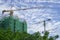 Upward view of precast building and large tall Tower Crane moving machine in construction work, scaffolding cover by green net