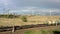 URAL REGION, RUSSIA - JULY 10, 2019: Freight train moving on background of windmills, drone shot under grey sky