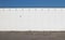 Urban background. Concrete road, a white wall made of square bricks and blue sky