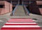 Urban background, red and white pedestrian crossing in front of a stone stairs of a modern building