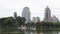 Urban cityscape: green trees and large lake in front of skyscrapers in downtown. Rise buildings and city park at the