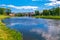 Urban clean pond with green grass around it. There are ducks in it